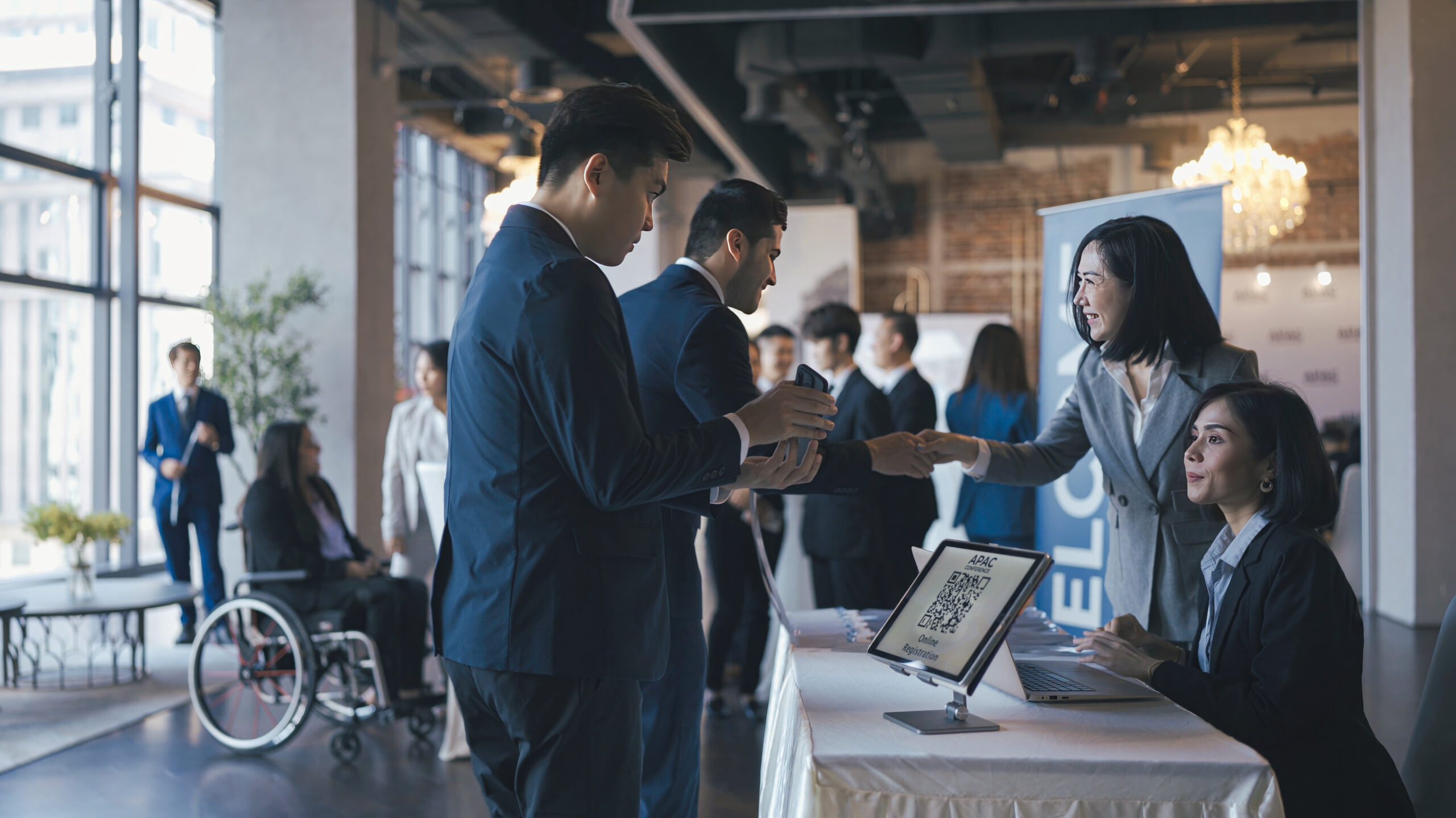 Asian event participants guest registering at reception desk attending business conference seminar